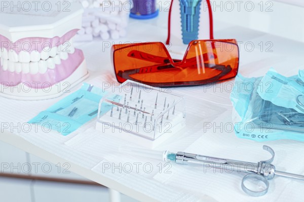 Various instruments, dental models, and hygiene items are laid out on the table in the dental office. natural light