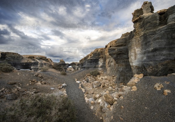 Eroded rock formations, volcanic landscape with dramatic cloudy skies, Ciudad Estratificada or Los Roferos, Antigua Rofera de Teseguite, Lanzarote, Canary Islands, Spain