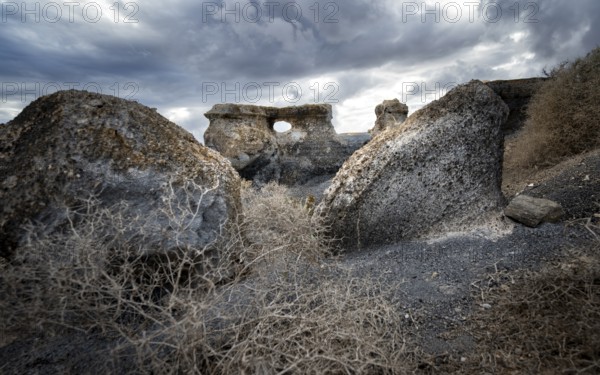 Eroded rock formations with rock tunnels, volcanic landscape with dramatic cloudy skies, Ciudad Estratificada or Los Roferos, Antigua Rofera de Teseguite, Lanzarote, Canary Islands, Spain