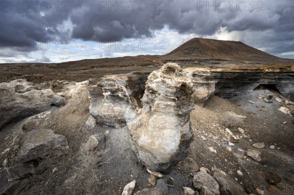 Eroded rock formations in volcanic landscape with dramatic cloudy skies, Ciudad Estratificada or Los Roferos, Antigua Rofera de Teseguite, Lanzarote, Canary Islands, Spain