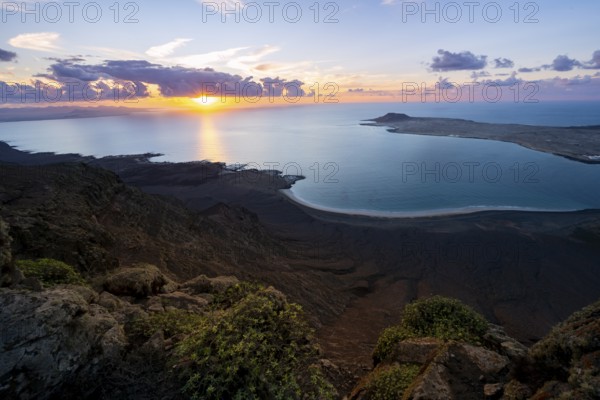 View from steep cliffs to sea and coast with sun stars, Mirador del Porrito viewpoint at sunset, Lanzarote, Canary Islands, Spain