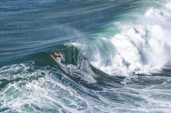 Surfers with their jet ski pilots in the Atlantic waves below Farol de Nazaré, Forte São Miguel, known as a surfer hot spot with monster waves between November and February of each year, Nazaré, Portugal