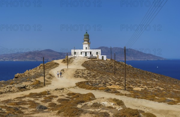 Mykonos, Cyclades, Greece - The Armenistis lighthouse in the north of the island is a landmark and a popular destination for tourists. In the back is the island of Tinos