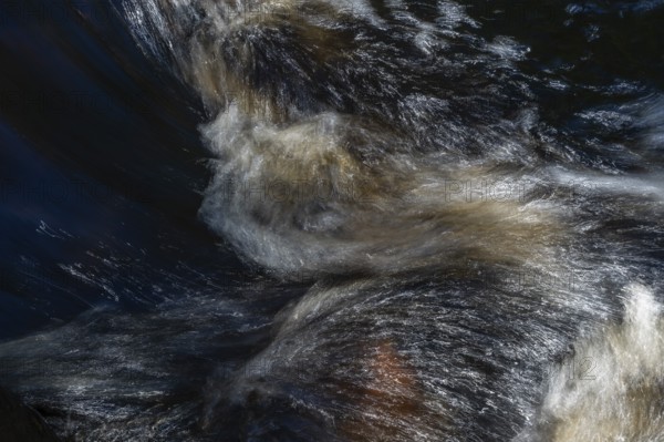 Stream flow with dark water, reflections and turbulences, long exposure, Sweden