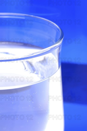 Glass with mineral water, small carbonated pearls on the edge of the glass, drinking water