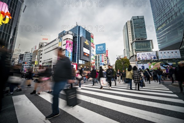 Crowd crossing zebra crossing on a large intersection, motion blur, back modern houses with colorful neon signs, long exposure, Shibuya Crossing, Shibuya, Tokyo, Japan