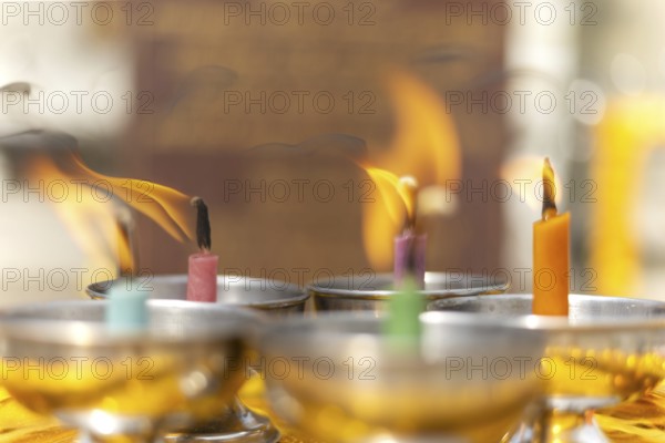 Oil lamps lit by believers as a symbol of the light of wisdom (the light dispels darkness and ignorance) in front of a Buddha statue, Wat Yannawa in the Sathon district, Bangkok, Thailand