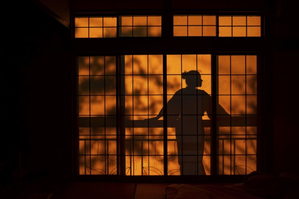 Shadows of a woman in kimono, on the balcony behind sliding shoji doors in a traditional Japanese house, Yamanouchi, Nagano, Japan