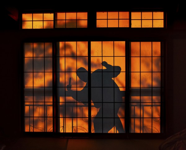 Shadow of a man, burglar with knife, assassin, ninja, on the balcony behind sliding shoji doors in a traditional Japanese house, Yamanouchi, Nagano, Japan