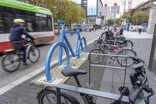 Bicycle parking spaces, with so-called leaning bars and a large blue bicycle silhouette, to make parking spaces visible at Bochum City Hall, North Rhine-Westphalia, Germany