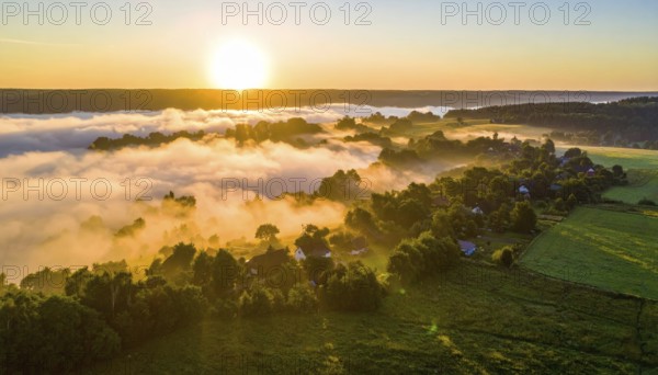 Sunrise over a fog covered village in a rural landscape, golden morning light, serene autumn atmosphere, hills and mountains in the background, AI generated