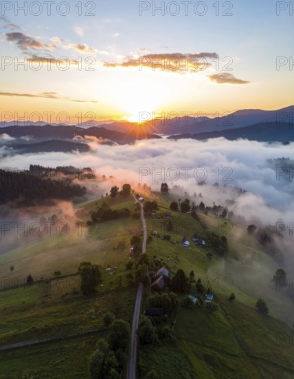 Sunrise over a fog covered village in a rural landscape, golden morning light, serene autumn atmosphere, hills and mountains in the background, AI generated