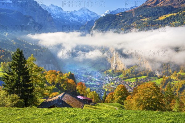 View from the village of the Lauterbrunnen Valley with Staubbach waterfall in autumn with morning fog, Wengen, Bernese Oberland, Canton of Bern, Switzerland