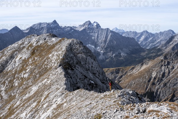 Hikers on the summit ridge of the Gamsjoch, behind rock faces of the Laliderer Spitze, eastern Karwendel, Tyrol, Austria