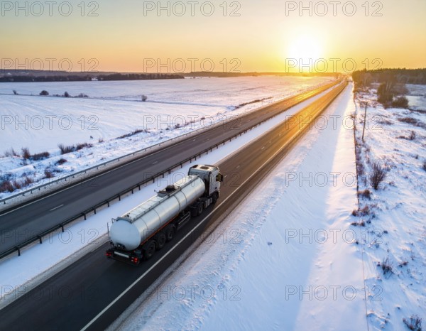 Petrol cargo truck lorry tanker driving on highway hauling oil products at sunrise, wide snowy landscape in winter, AI generated