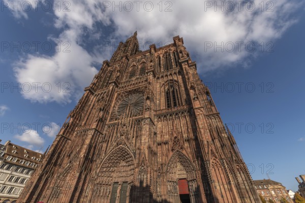Strasbourg's Notre Dame Cathedral stands majestically there. Its magnificent architectural details are clearly visible under the blue, cloudy sky. Bas Rhin, Alsace, France