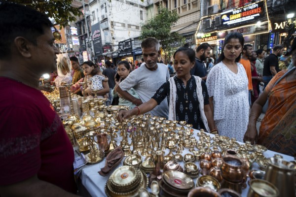People shop for bronze and other metal items at a roadside stall on Dhanteras, in Guwahati, Assam, India on 18 October 2025. On Dhanteras, people traditionally buy precious metals like gold, silver, or even new utensils, as it is believed this brings wealth and good luck into the household