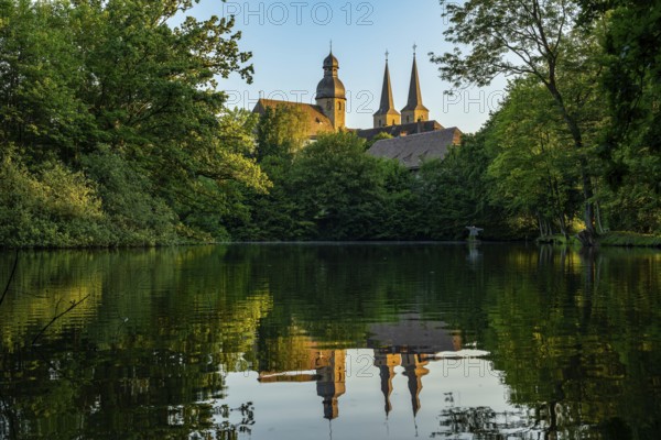 View of the monastery church of Marienmünster Abbey, a former Benedictine monastery, with reflection in the lake, Teutoburg Forest, North Rhine-Westphalia, Germany