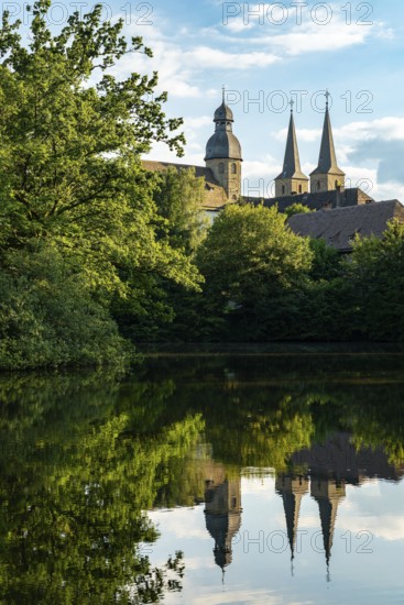 View of the monastery church of Marienmünster Abbey, a former Benedictine monastery, with reflection in the lake, Teutoburg Forest, North Rhine-Westphalia, Germany