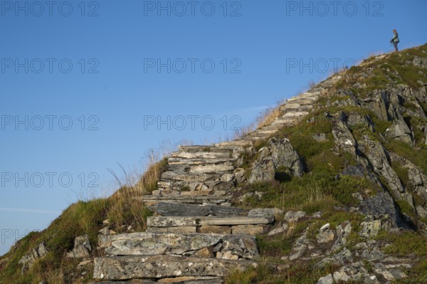 Woman with hiking poles walking up Rørsethornet stone stairs, with 3292 steps one of the longest continuous stone stairs in the world, Sherpat stairs or Midsund stairs or Midsundtrappene, Rørsethornet hike, Otroya or Otrøya island, Møre og Romsdal, Norway
