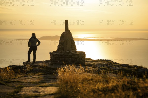 Woman standing next to cairn and looking at the sea, Rørsethornet stone staircase, with 3292 steps one of the longest continuous stone staircases in the world, Sherpat stairs or Midsund stairs or Midsundtrappene, Rørsethornet hike, evening mood, Otroya or Otrøya island, Møre og Romsdal, Norway