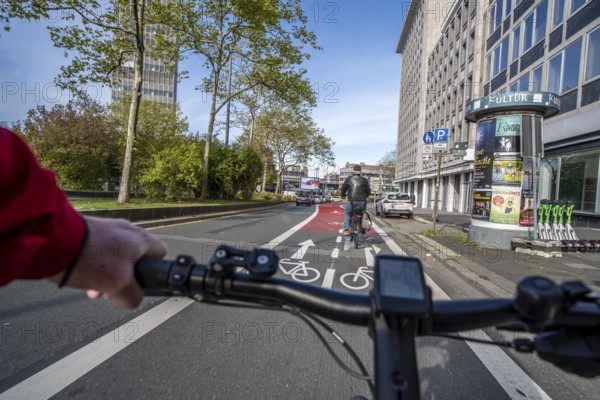 Riding a bike in a bike lane, marked in red to attract the attention of motorists, between 2 lanes, Huyssenallee, in front of Europaplatz, in the city centre of Essen, North Rhine-Westphalia, Germany