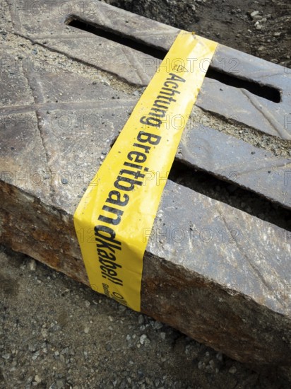 Flapping tape with the indication of an installed fibre optic cable at a construction site in Wuppertal, Germany