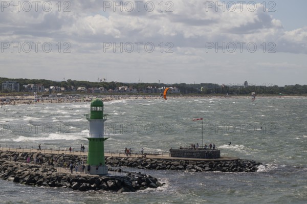 Green and white lighthouse, pier light Westmole in front of lively beach and hotels in the background, waves, Warnemünde, Rostock, Mecklenburg-Western Pomerania, Germany