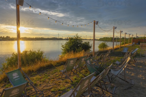 View from the outdoor area of a restaurant at Lankenauer Höft over deckchairs through a string of lights onto Neustadt harbour in the evening light, Weser, Bremen, Germany