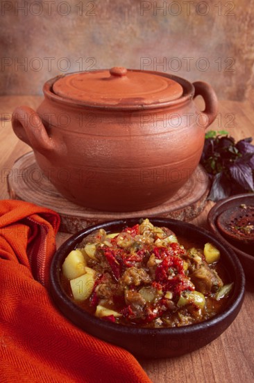 Chanakhi, a Georgian dish. in a clay pot, on a wooden table, stewed meat with vegetables, homemade, no people
