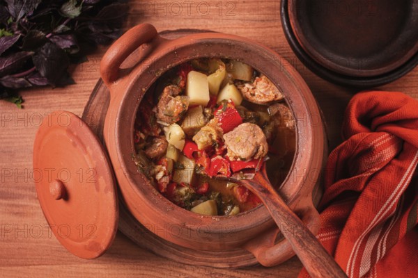 Chanakhi, a Georgian dish. in a clay pot, on a wooden table, stewed meat with vegetables, homemade, no people
