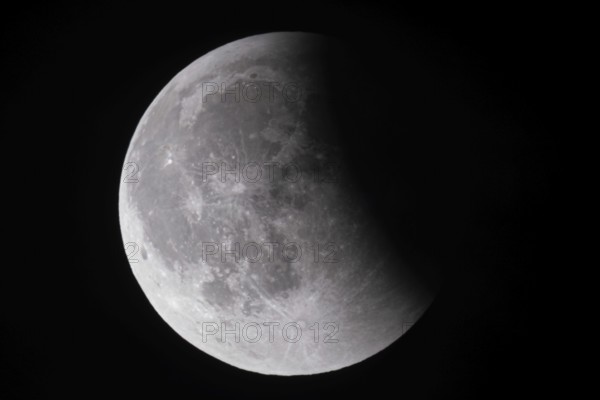 After a total lunar eclipse, the moon appears shortly after its rise in the evening sky as a so-called blood moon in front of it then begins to emerge from the Earth's umbra, Frankfurt am Main, Hesse, Germany