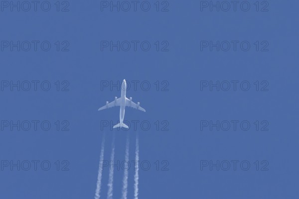 Airbus A340-300 jet aircraft of Lufthansa airlines in flight in a blue sky with vapour trails or contrails behind, England, United Kingdom