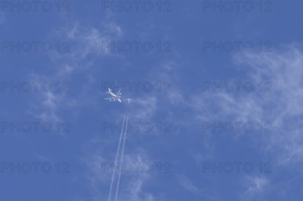 Two airliners Airbus A380 jet passenger aircraft of Emirates airlines and a Boeing 737 of Norweign Air flying in a blue sky, England, United Kingdom