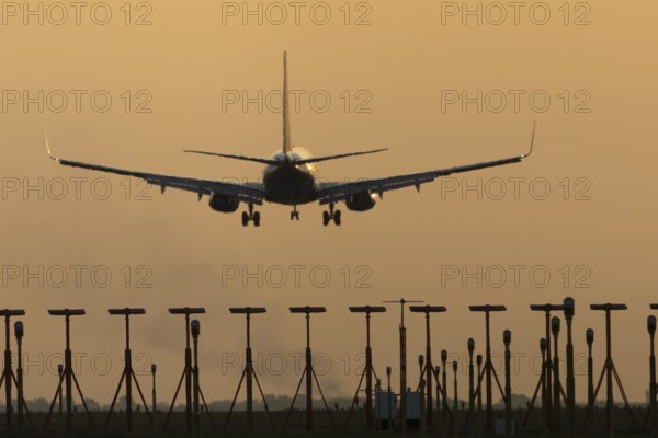 Boeing 737 jet passenger aircraft of Ryanair airlines landing over runway lights at sunset, London Stansted airport, Essex, England, United Kingdom