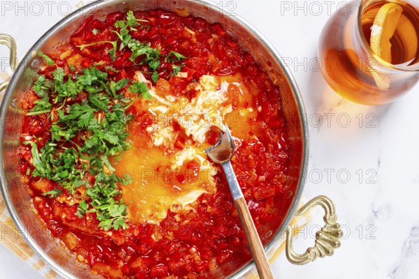 Traditional Turkish dish, scrambled eggs with tomatoes, Menemen, with herbs, in a frying pan, close-up, no people
