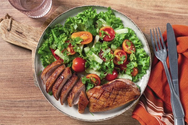 Delicious grilled duck breast served with fresh garden salad and cherry tomatoes at a rustic dining table