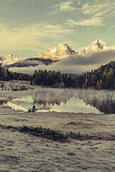 Lake Staz near Sankt Moritz in the Engadin in Switzerland. Morning atmosphere with fog in autumn. Water reflection and snow-covered mountains in the background