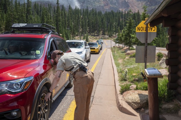 Colorado Springs, Colorado - A Pikes Peak ranger checks the temperature of brakes on a car descending 14, 115' Pikes Peak. If the brakes have become hotter than 300 degrees F, travelers must stop to let the brakes cool before continuing their descent