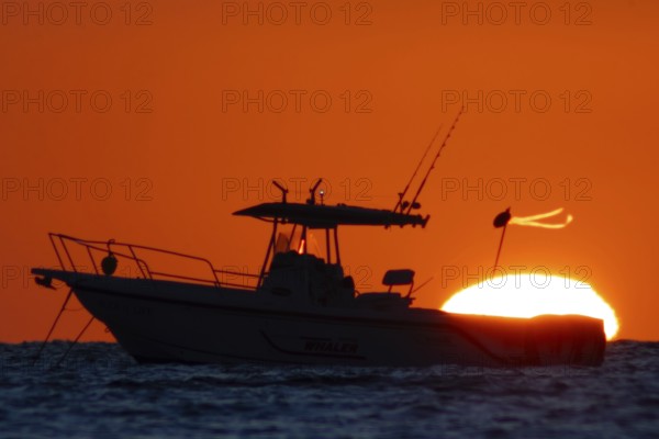 The sun rises behind a boat on the Costa Rei, a coastal stretch of the Italian Mediterranean island of Sardinia, Monte Nai, Costa Rei, Sardinia, Italy