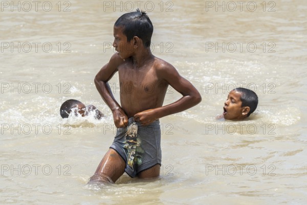 Children bathe in the Brahmaputra River to seek relief from the intense summer heat in Guwahati, India, on June 26, 2025