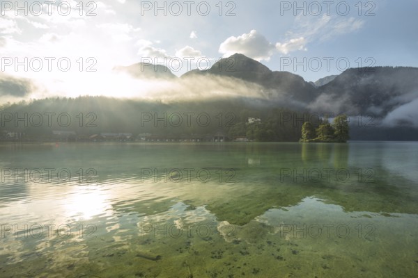 Mystical morning at Königssee in Schönau with boathouses and Christlieger. Sunrise and beautiful wafts of mist over the Königssee in the basin
