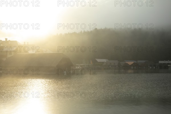 Mystical morning at Königssee in Schönau with boathouses. Sunrise and beautiful wafts of mist over the Königssee in the basin