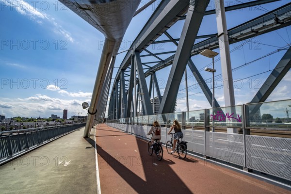 Cycle and pedestrian bridge Snelbinder Brug, over the river Waal near Nijmegen, was added to the existing railway bridge, fast cycle path connection from the city centre of Nijmegen and the new housing estates in the Waalsprong district, Netherlands