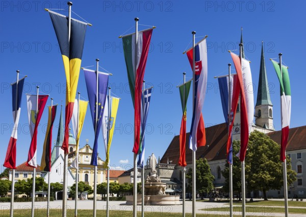 National flags at Kapellplatz with the collegiate parish church of St Philip and St James, place of pilgrimage, Altötting, Upper Bavaria, Bavaria, Germany