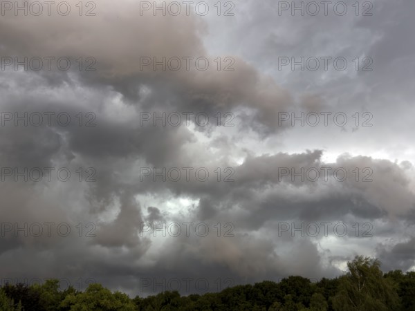 Dark discoloured thunderclouds Cloud roll moves over forest area above grey clouds Rain clouds herald thunderstorms, Germany