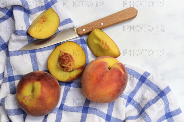 Peach with knife on kitchen towel, peach halves, Prunus persica
