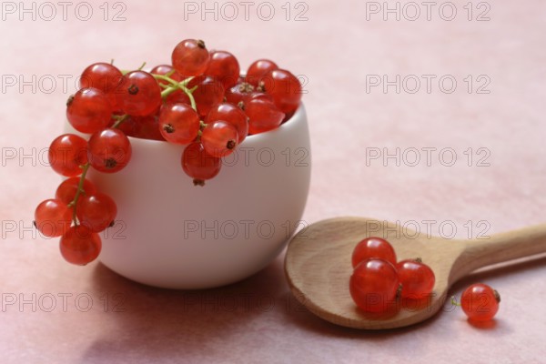 Redcurrants in small bowls and wooden spoon, Ribes rubrum