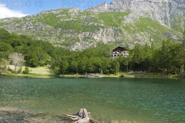 View of mountain lake Lago Grande near Moncenisio in Val Cenischia in the Graian Alps, behind it chalet on the lake, Moncenisio, Piedmont, Italy