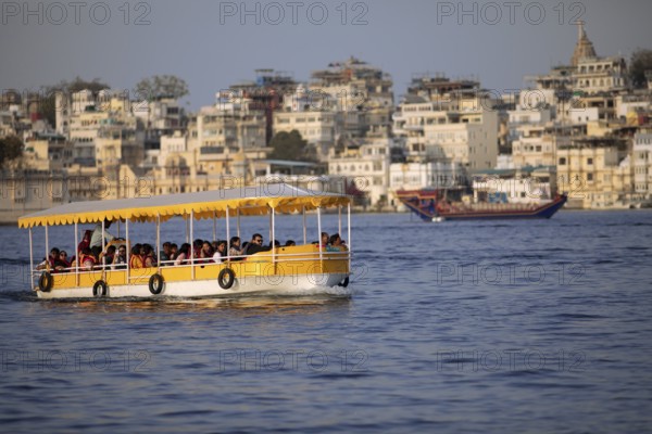 Excursion boats on Lake Pichola, behind the old town in the evening light, Udaipur, Rajasthan, India
